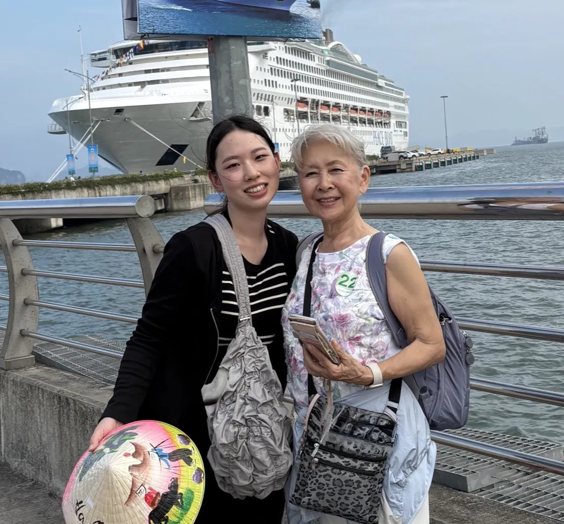クルーズ船の寄港地で、旅行中のシニアの女性と並んで笑顔を見せる代表