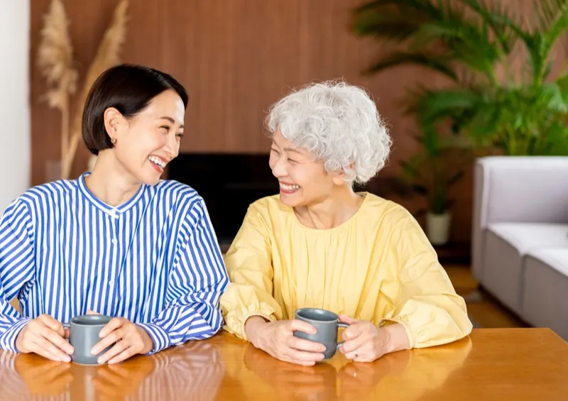 お茶を飲みながら笑い合うスタッフとシニアの女性